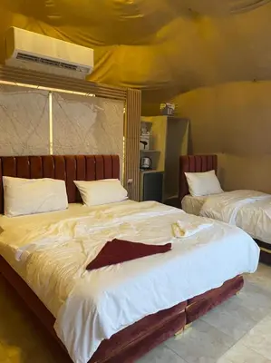 a bedroom with two beds with a cat laying on them at Jawharat Rum camp in Wadi Rum