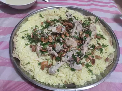 a plate of rice with meat and mushrooms on a table at Issa Snaffi Bedouin home in Wadi Musa