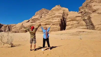 two people standing in the desert with their hands up at The sunset of Wadi Rum in Wadi Rum