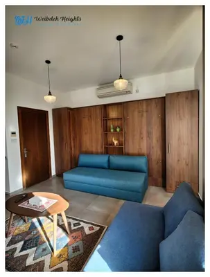 a living room with a blue couch and a table at Weibdeh Heights Hotel Suites in Amman