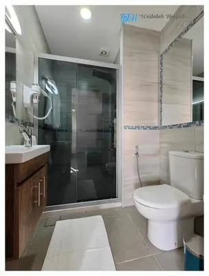 a bathroom with a shower and a toilet and a sink at Weibdeh Heights Hotel Suites in Amman