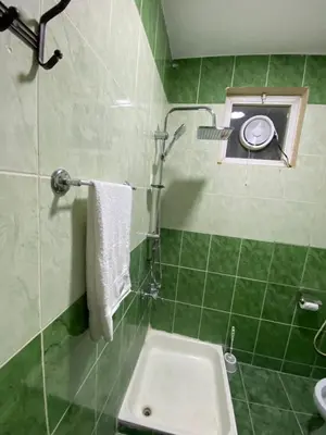 a green tiled bathroom with a toilet and a sink at Hustle's look in Wadi Musa