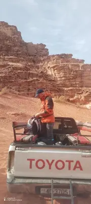 a man standing on the back of a toyota truck in the desert at Rum desert camp in Wadi Rum
