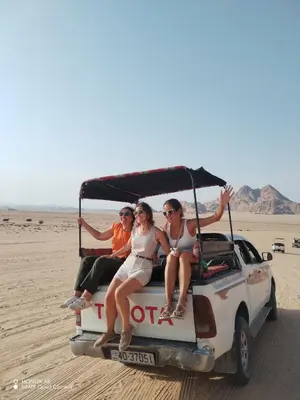 three people sitting on the back of a golf cart in the desert at Rum desert camp in Wadi Rum