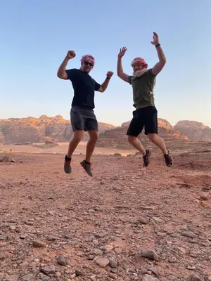 two men jumping in the air in the desert at Rum desert camp in Wadi Rum
