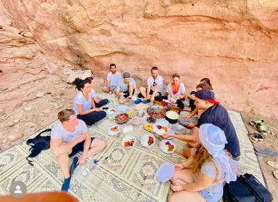 a group of people sitting around a table with food at Bedouin Desert Cave in Wadi Rum