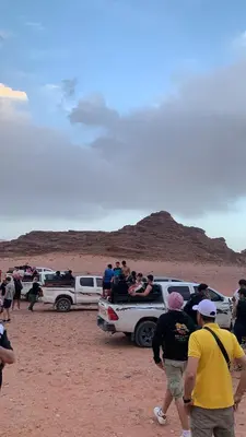 a group of people standing around vehicles in the desert at Rum Awaad luxury camp in Wadi Rum