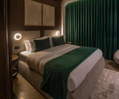 a bedroom with a large bed with green curtains at Bratus Hotel in Aqaba