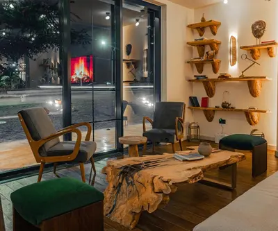 a living room with chairs and a wooden table and a room with windows at Bratus Hotel in Aqaba