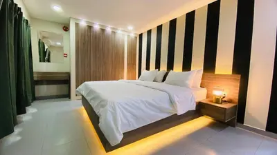 a bedroom with a white bed with a striped wall at 7 Days Hotel in Umm Uthainah
