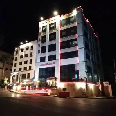a large building with lights on it at night at 7 Days Hotel in Umm Uthainah