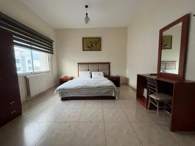 a bedroom with a bed and a dresser and a mirror at Nojoom Hotel in Amman