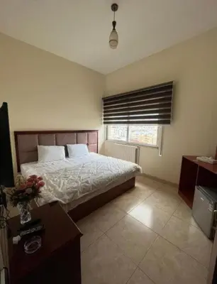 a bedroom with a bed and a table and a window at Nojoom Hotel in Amman