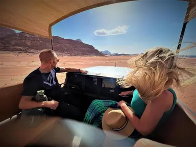 a man and a woman in a jeep in the desert at The Villas - Bedouin Boutique Resort in Wadi Rum