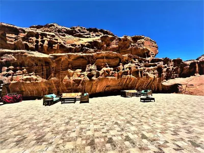 a rock wall with tables and benches in front of it at The Villas - Bedouin Boutique Resort in Wadi Rum