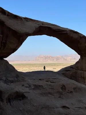 a man standing in front of an arch in the desert at Scarlet Luxury Camp Wadi Rum in Wadi Rum