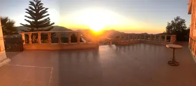 a sun setting over a balcony with a view of the mountains at Cozy House in Wadi Musa