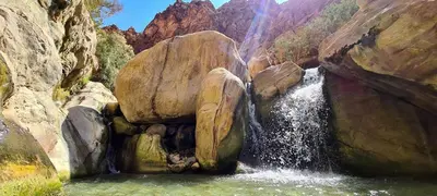 a waterfall in a pool of water between rocks at Dana Sunset Eco Camp in Dana