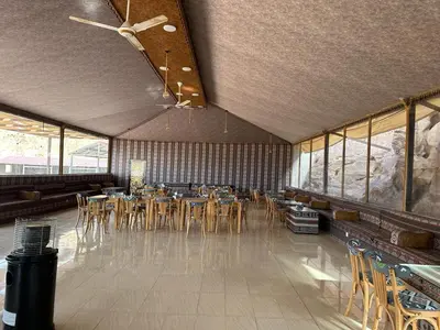 a dining room with tables and chairs and windows at Nara Wadi RUM Camp in Wadi Rum