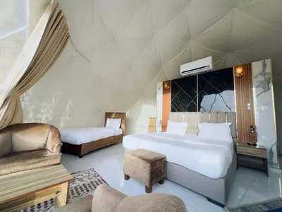 a bedroom with two beds and a chair and a couch at Rum Kingdom Camp in Wadi Rum