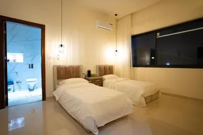 two beds in a room with a large window at مزرعة وفيلا الريان وادي رم in Ruʼaysat al Khālidī