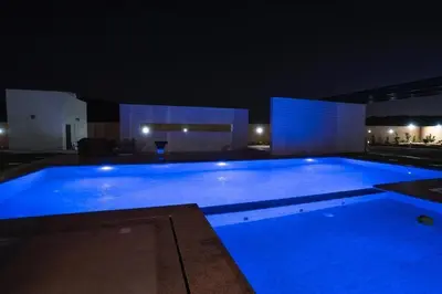 a large swimming pool lit up at night at مزرعة وفيلا الريان وادي رم in Ruʼaysat al Khālidī