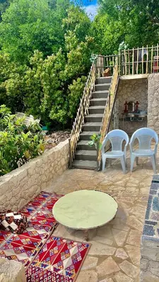 a patio with two chairs and a table and stairs at Oak Farm مزرعة الملّول in Ajloun