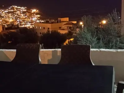 a table and chairs on a balcony at night at Petra Inn House in Wadi Musa