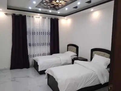 two beds in a room with white sheets at Petra Inn House in Wadi Musa