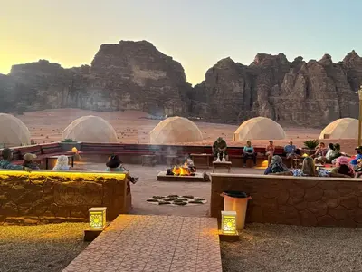 a group of people sitting around a fire in domes in a desert at Wadi Rum Alia Luxury Camp in Wadi Rum