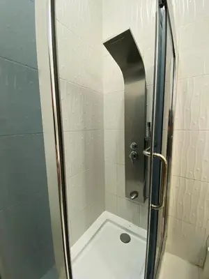 a shower with a glass door next to a bath tub at Contemporary Semi Villa Apartment with Private Entrance in Khalda in Amman
