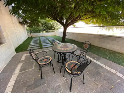 a patio with a table and chairs and a tree at Contemporary Semi Villa Apartment with Private Entrance in Khalda in Amman