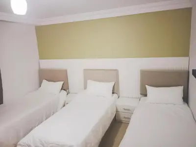 three beds in a room with white sheets at Pomegranate Tree in Wadi Musa