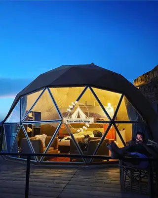 a man laying on a chair in a glass igloo at RUM WORLD BUBBLE lUXURY CAMP in Wadi Rum