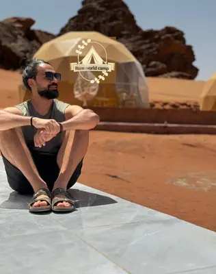 a man sitting on the ground in front of a building at RUM WORLD BUBBLE lUXURY CAMP in Wadi Rum