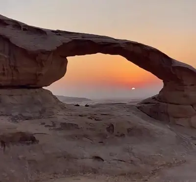 an arch in the desert with the sunset in the background at Wadi rum desert sky in Wadi Rum