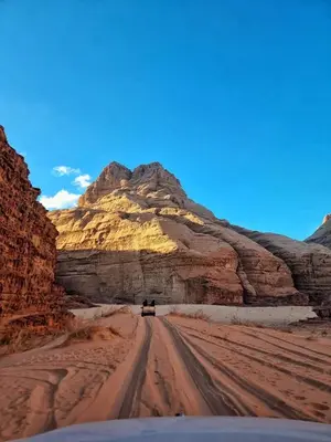 a car driving down a dirt road in the desert at Rum Royal Dunes Camp & tour in Wadi Rum