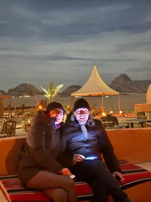 two women sitting on a bench in front of the beach at Rum Royal Dunes Camp & tour in Wadi Rum