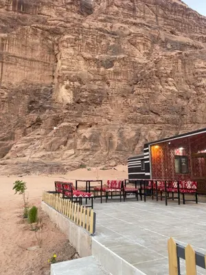 a building with tables and chairs in front of a mountain at Rum Royal Dunes Camp & tour in Wadi Rum
