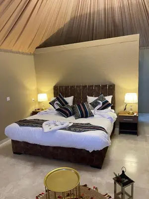a bedroom with a large bed with two tables and two chairs at Rum Royal Dunes Camp & tour in Wadi Rum