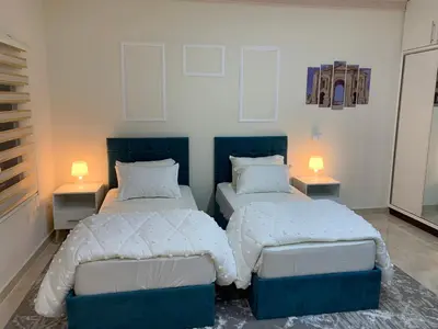 two beds in a room with two lamps on tables at Tayoon Host in Jerash
