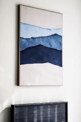 a painting hanging on a wall above a fireplace at Abdali Views Apartments in Amman