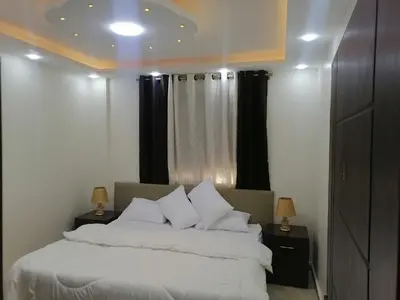 a bedroom with a white bed with black curtains at Petra Guests home in Wadi Musa