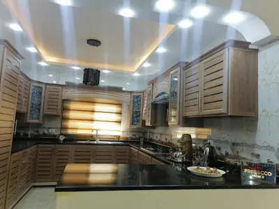 a kitchen with wooden cabinets and a black counter top at Petra Guests home in Wadi Musa