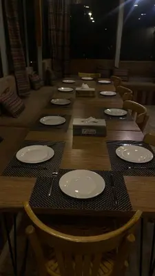 a long wooden table with white plates on it at Raqeem Hotel in Wadi Musa
