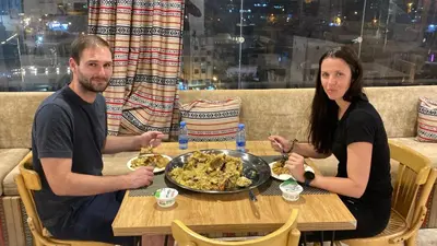 a man and woman sitting at a table with a plate of food at Raqeem Hotel in Wadi Musa