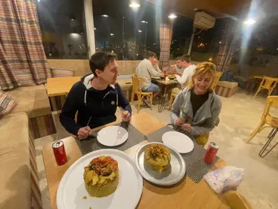 a group of people sitting at a table with plates of food at Raqeem Hotel in Wadi Musa
