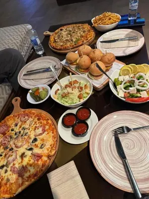 a table with pizzas and plates of food on it at Raqeem Hotel in Wadi Musa