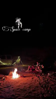 a car is driving past a bonfire at night at Wadi Rum Space camp in Wadi Rum