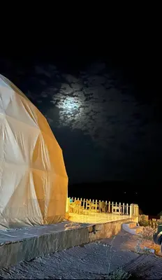 a white tent with the moon in the background at Wadi Rum Space camp in Wadi Rum